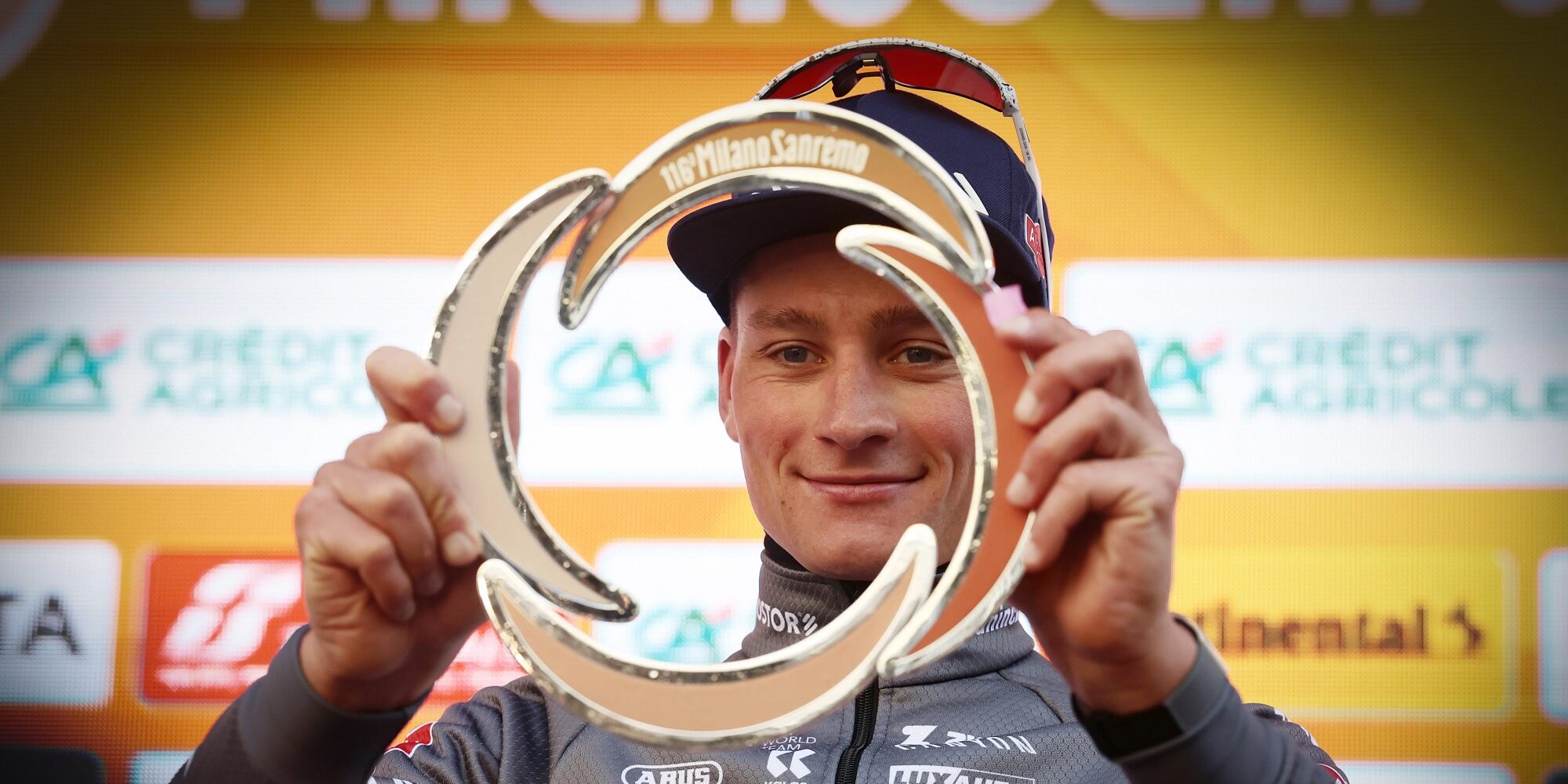 Mathieu van der Poel holding Milan-Sanremo trophy on podium wearing Dutch champion jersey