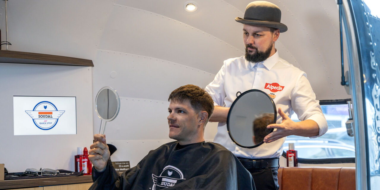 Jasper Stuyven getting a haircut at Alpecin Barbershop holding a mirror