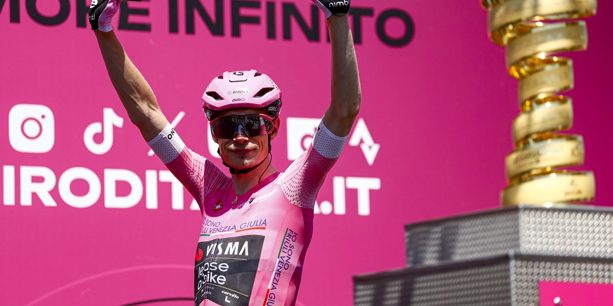 Jonas Vingegaard celebrating in pink Giro d'Italia leader jersey with trophy visible