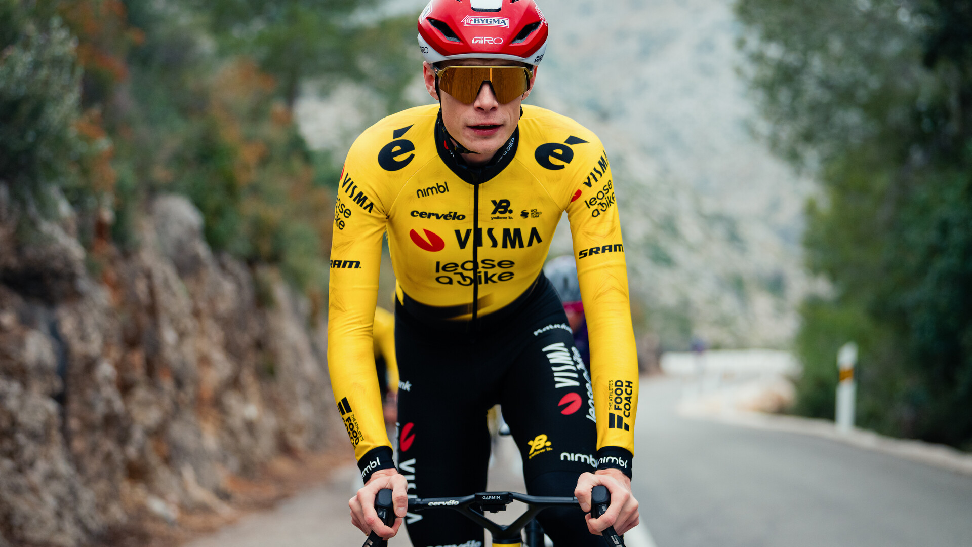 Cyclist in Visma-Lease a Bike yellow team jersey riding on road with blurred background