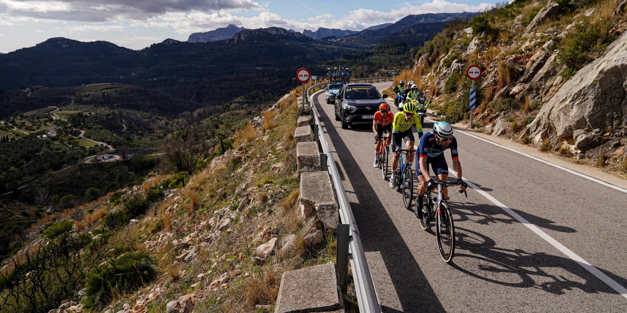 Breakaway group cycling on mountain road during Gran Premi Valencia with dramatic valley views